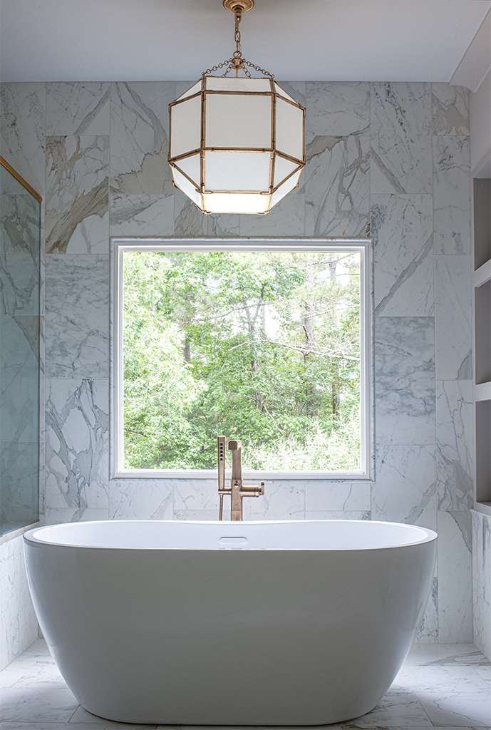 Atlanta’s Top Interior Designer Nesbit Ferry Road Residence Project Master Bath Tub, window, marble wall and light fixture.